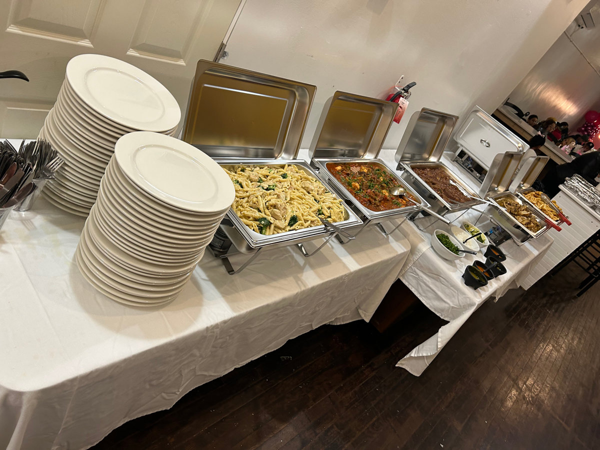 Full catering buffet with trays of chicken, birria, rice and beans